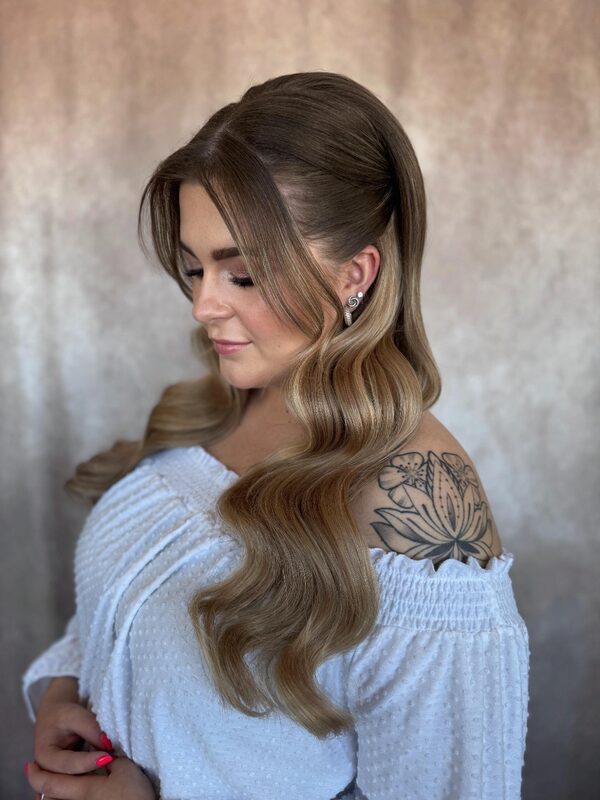Model met lange blonde golven en een tatoeage op de schouder