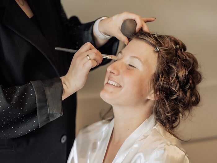 Danique brengt make-up aan bij een bruid in een zijden ochtendjas