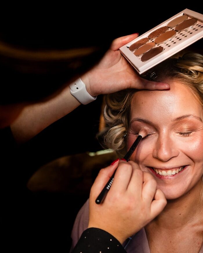 Danique brengt make-up aan bij een bruid die haar ogen gesloten houdt