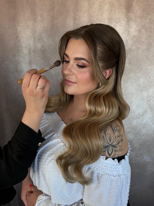 Danique brengt make-up aan bij een model met lange blonde golven