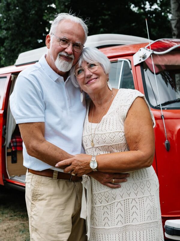 Ouder stel bij een rood Volkswagenbusje