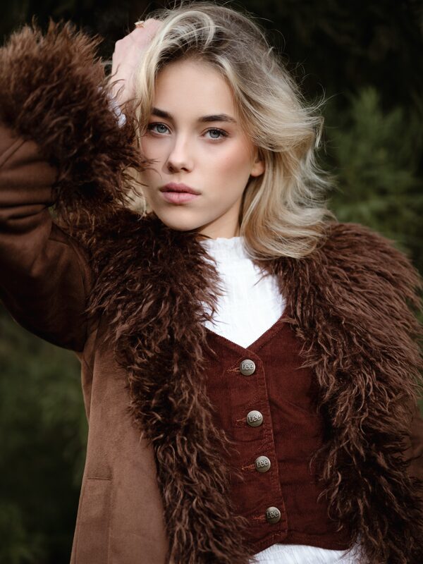 Blond model in bruine bontjas in het bos