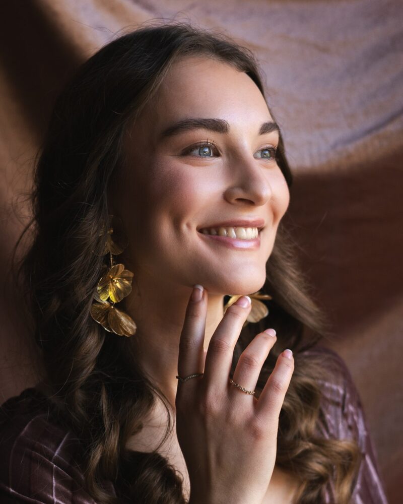 Lachend model met gouden oorbellen en roze tule, in warm licht