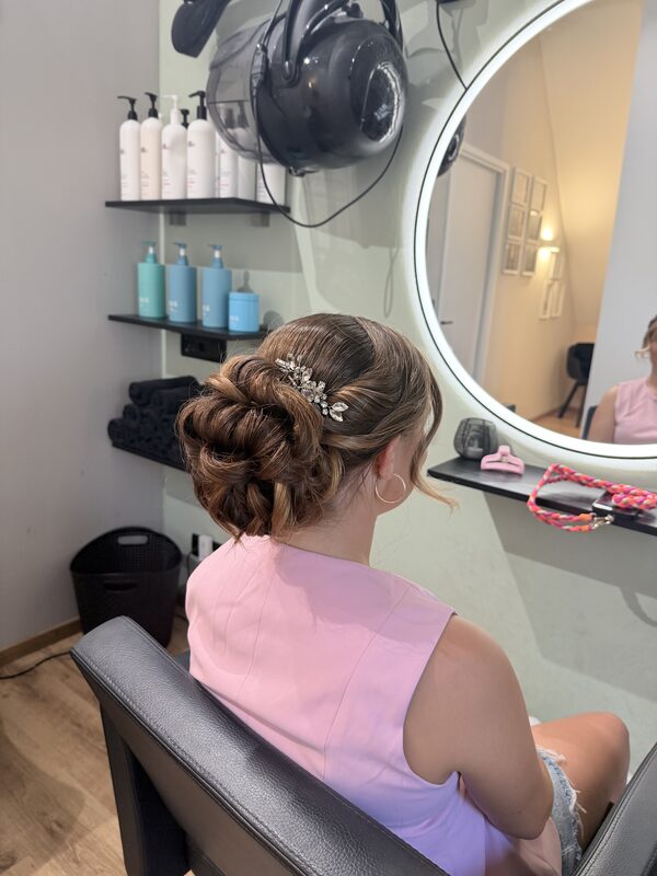 Opgestoken kapsel met haaraccessoire, gezien vanaf de achterkant in de salon