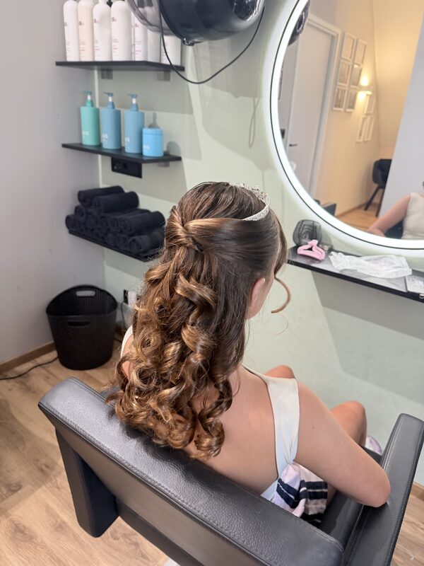 Halflang haar met losse krullen, gezien vanaf de achterkant in de salon