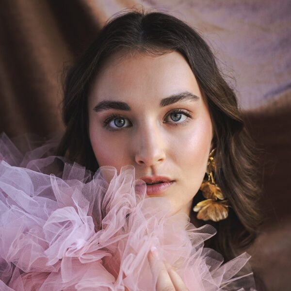 Model met gouden oorbellen en roze tule