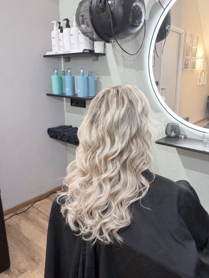 Lange blonde golven met hair extensions, gezien vanaf de achterkant in de salon